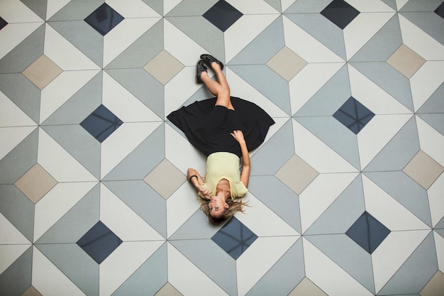 Woman young adult beautiful happy in a large hall with a floor with geometric tiles top view