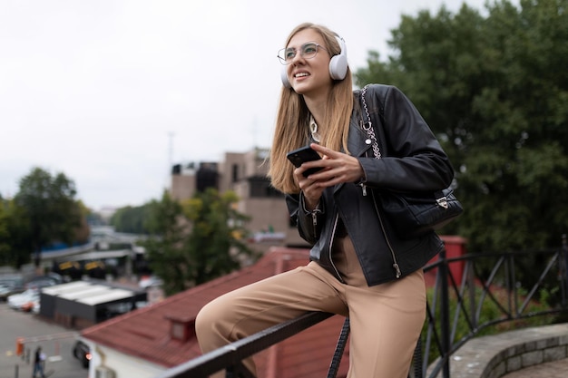 Woman young journalist listening to music in headphones on the street