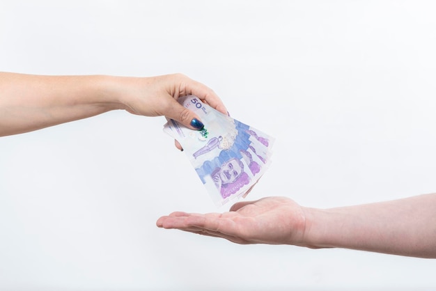 Woman39s hand depositing Colombian currency banknotes on man39s hand