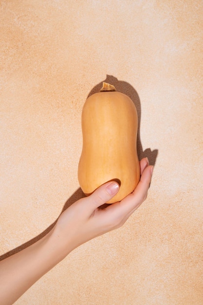 Woman39s hand holding small halloween pumpkin on beige background Holiday decoration concept