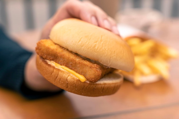 A woman39s hand holds a burger with fish fillet Fast food a snack