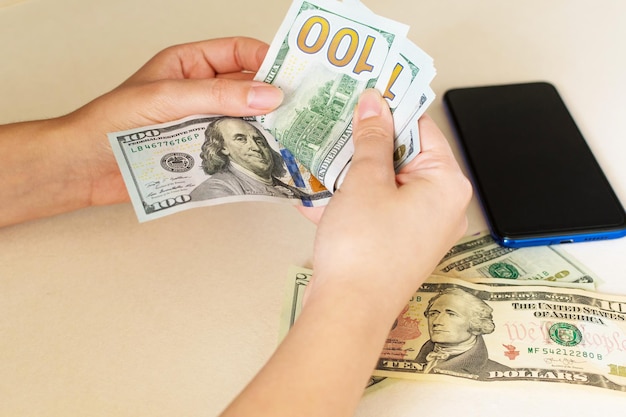 Woman39s hands counting dollar bills on white desk