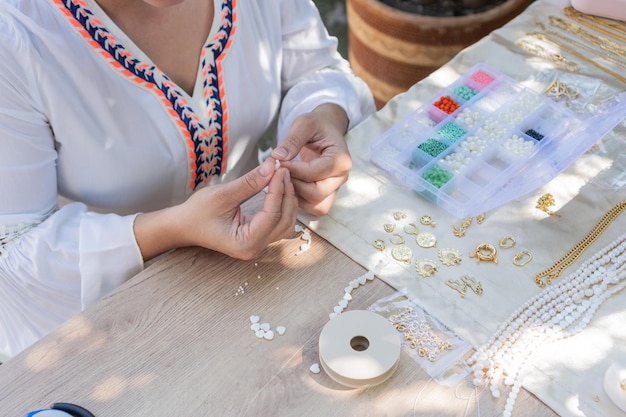 A woman39s hands making necklaces in her workshop