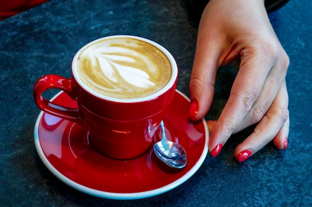 womans hand next to a cup of coffee