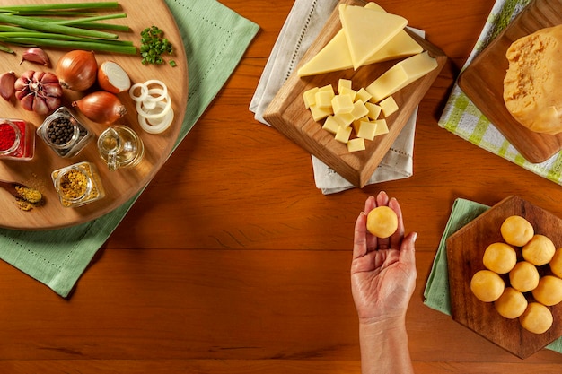 Womans hand holding brazilian cheese stuffed croquette bolinha de queijo on a wooden table Top view