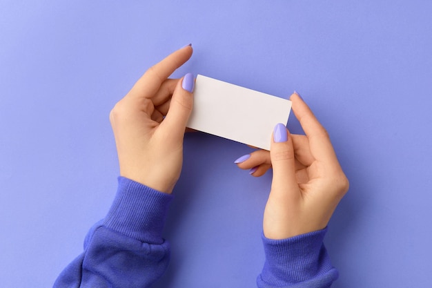 Womans hand holding business card on purple background business work template mockup