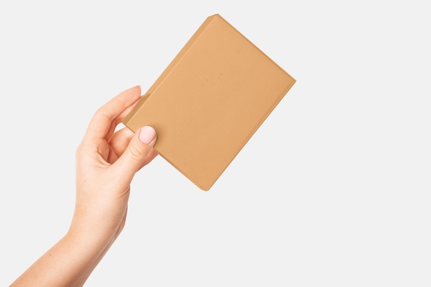 Womans hand holding a cardboard box on a light background