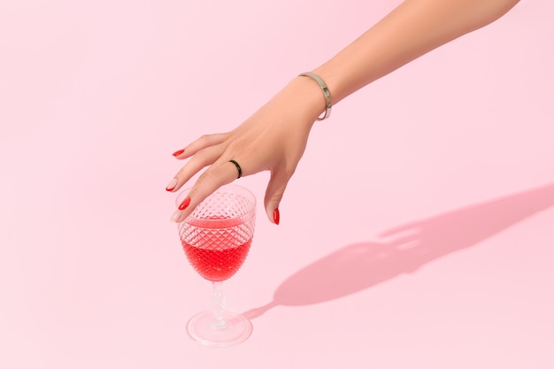 Womans hand holding glass on pink background manicure design trends