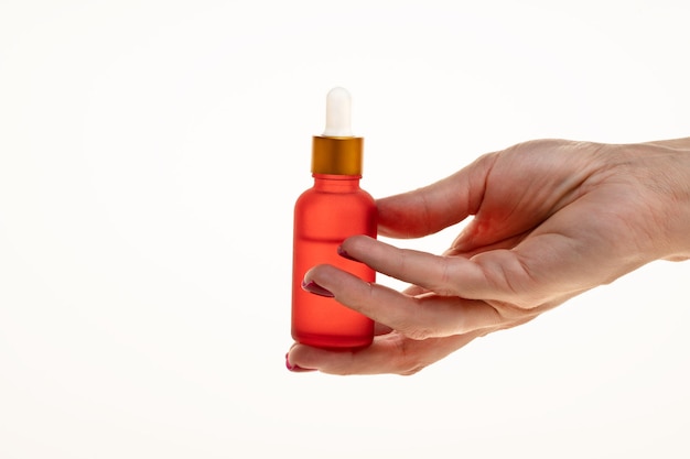 Womans hand holding a red dropper bottle with serum for face or body smoothing and antiaging