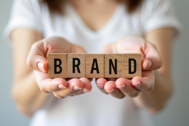 Photo a womans hand holding a wooden block with the word brand