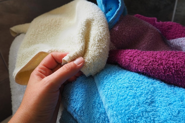 A womans hand is feeling a cotton colored towel from a basket with dirty laundry laundry sorting and