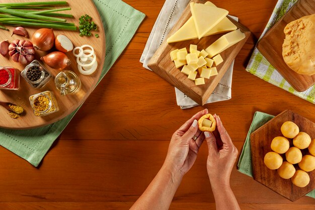 Womans hand preparing brazilian cheese stuffed croquette bolinha de queijo on a wooden table Top view