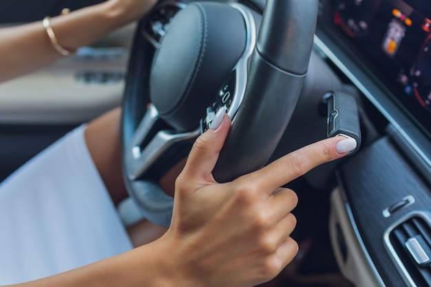 Womans hand switches the lobes of the gear selector on the steering wheel hand is switching car gear lever close up shot of a manual gear changing paddle on a cars steering wheel