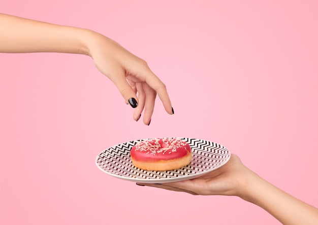 Womans hand takes tasty donut on pink mockup template for bakery