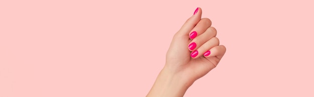 Photo womans hand with trendy manicure on pastel pink background beauty salon concept