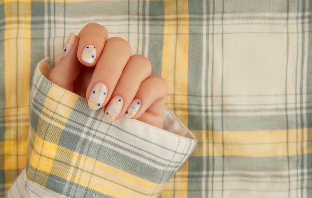 Womans hand with trendy polka dot summer manicure