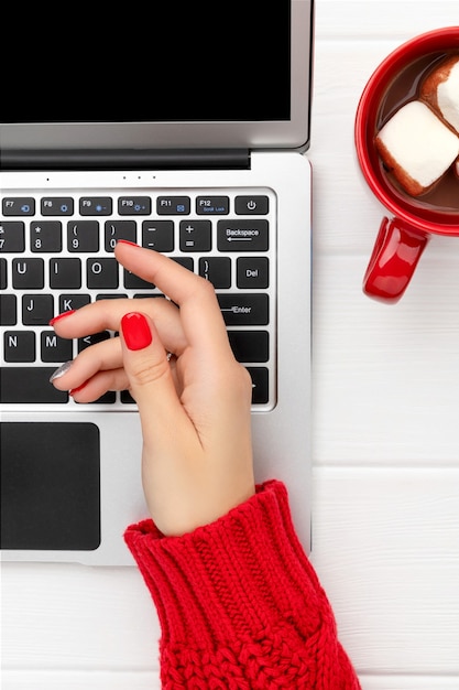 Womans hand with trendy red manicure with laptop