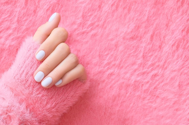 Womans hand with white nail design on pink background manicure pedicure beauty salon concept