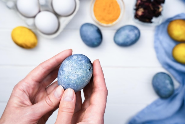 Photo womans hands hold a painted easter egg the process of dyeing easter eggs with natural dyes at home closeup top view