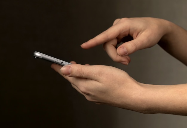 Womans hands using a smartphone on a dark background