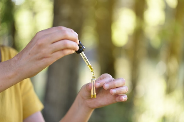 Womans hands with essential oil dropper in the open air