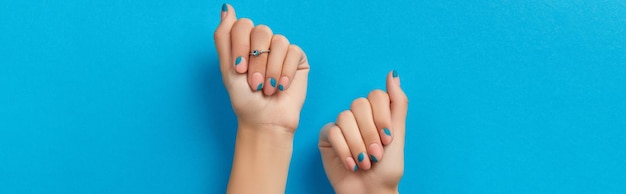 Womans hands with summer manicure on blue background