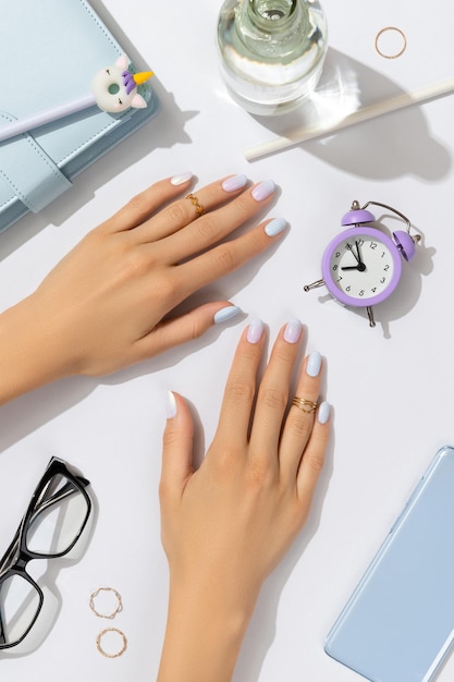 Womans hands with trendy manicure on blue background summer nail design