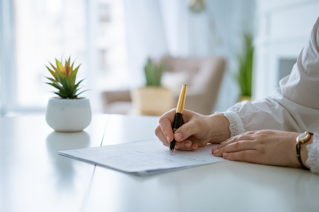 Womans hands writing on sheet with a pen hands of businesswoman working with documents