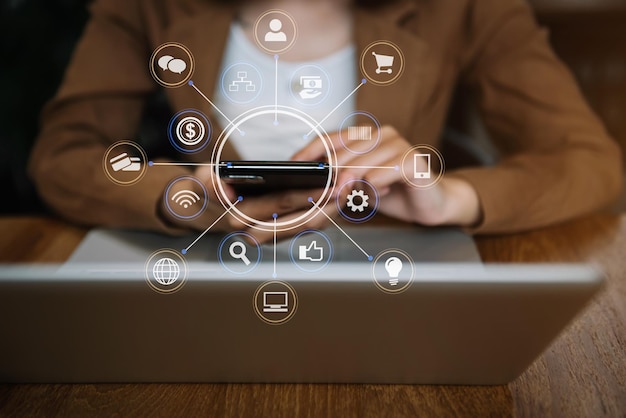 Women are using a mobile phone wifi connection on the desk with a laptop in the morning.