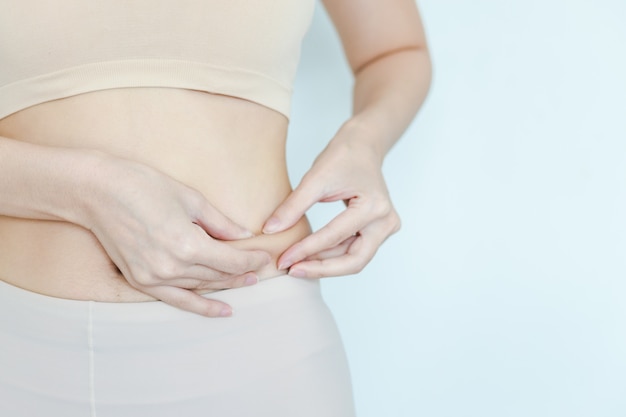 Women catch fat on the stomach to see how she reduced belly. girl testing fat layer on waist