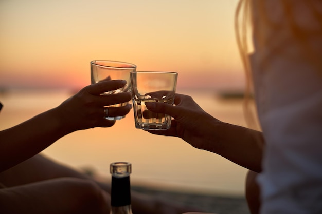 Women clink glasses with white wine on the beach girlfriends cheerfully celebrate vacation and