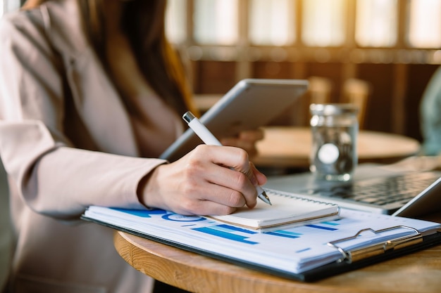 Women counting coins on calculator taking from the piggy bank. hand holding pen working on calculator to calculate on desk about cost at home office.