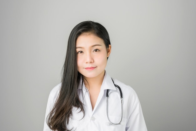 The women doctor stands and has stethoscope hanging on his neck. 