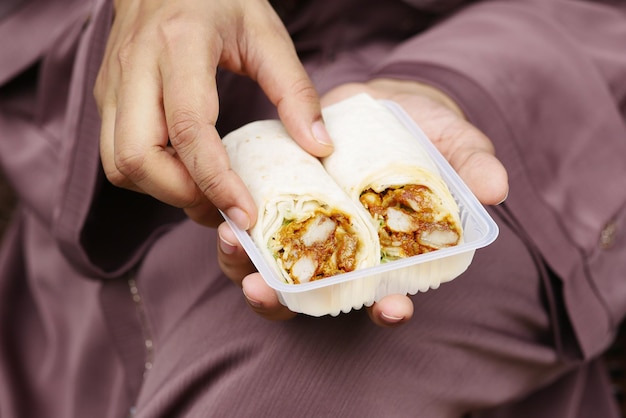 Women eating chicken warp sitting on park bench take out food concept