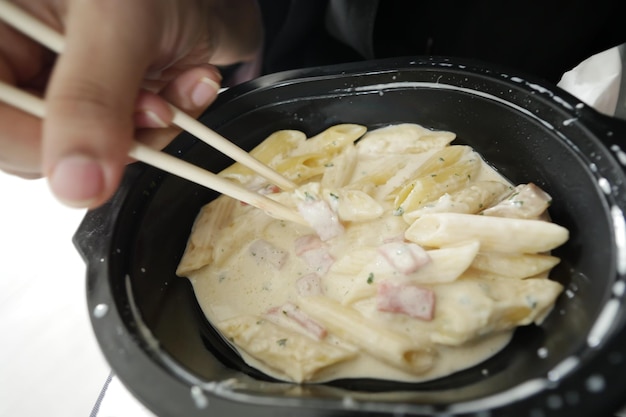 Women eating take away cooked pasta in a plastic container