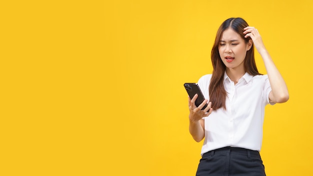 Women feel confused while reading data on smartphone with empty space on isolated yellow background