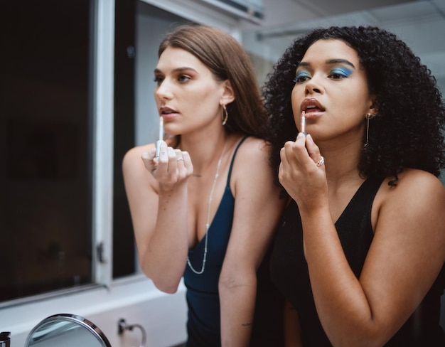 Women friends and cosmetics at mirror in bathroom for beauty wellness and makeup in night together Black woman girl and model with lipstick dark aesthetic and support for cosmetic at party