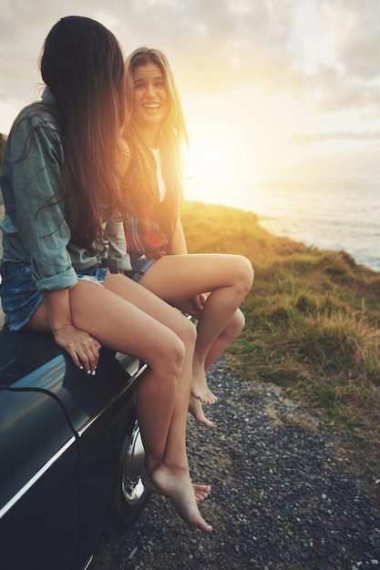 Women friends road trip and sunset in nature for travel adventure and freedom while happy outdoor Funny girls on a car while talking on vacation drive or journey with transport and ocean view