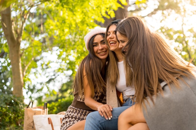 Women friends sitting hugging in a park in autumn at sunset lifestyle and autumnal outfit