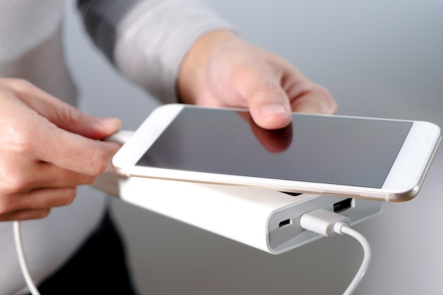 The women hand hold the phone and charger, powerbank and smart phone is connecting