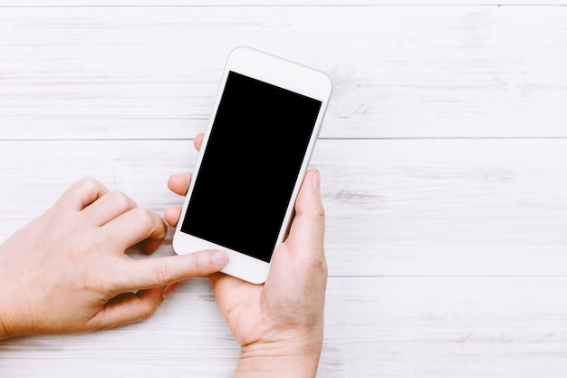 Women hand holding smartphone on wooden background