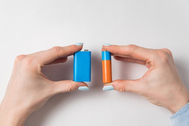 Women hands holding generic AA and PP3 batteries Accumulator on white background