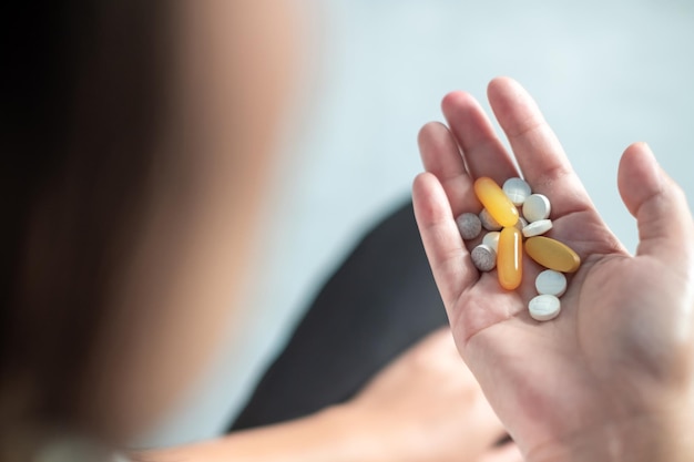 Women hands holding pills diffrent shape and colors top viewHealthcare and medical concept