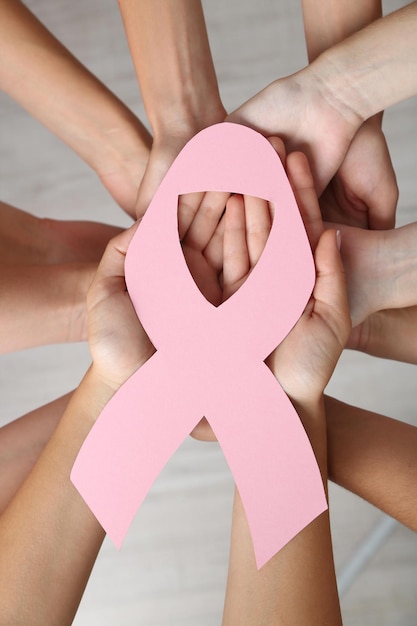 Women hands joined in circle holding breast cancer symbol