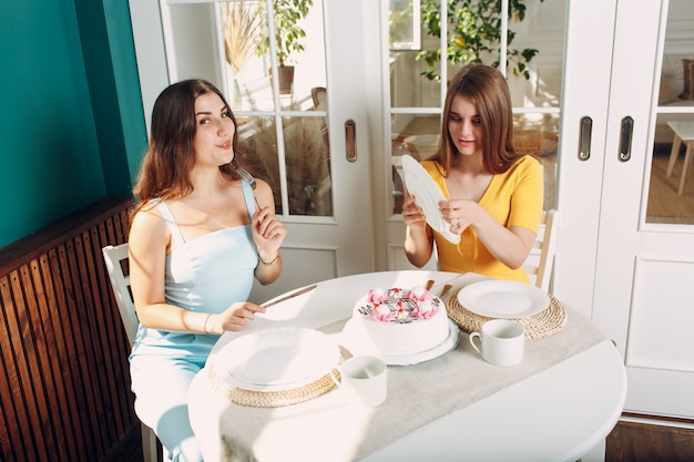 Women happy friends at home sitting and smiling with white birthday cake.