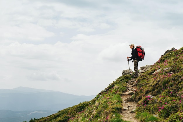 Women hiking with backpack holding trekking sticks mountains sky view