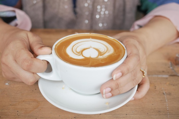 Women holding a cup of coffee on table