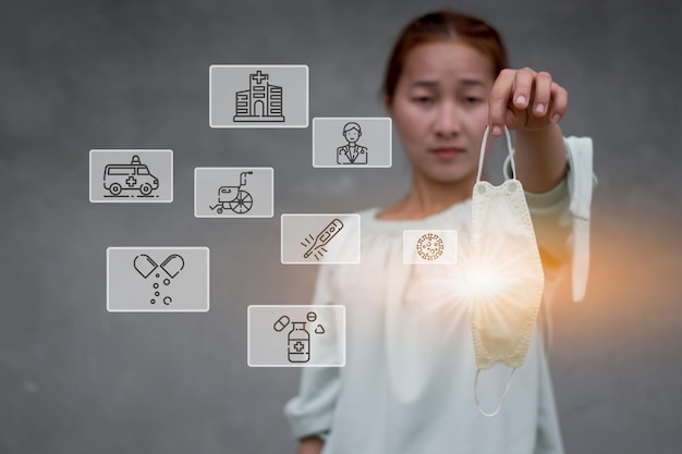 A women holding the mask with computer graphic light and virus hospital related icon around