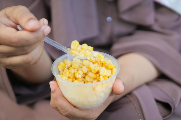 Women holding a plastic bowl of organic sweet corn