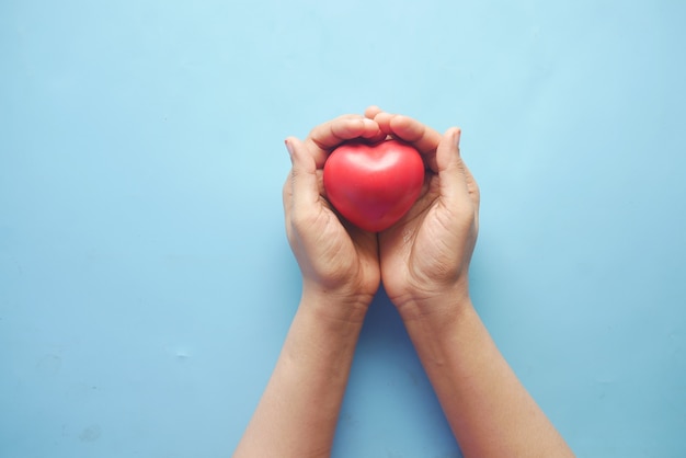 women holding red heart on blue background